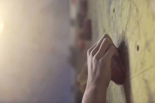 女性攀登者抓紧攀登墙图片下载