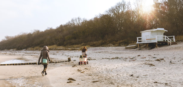 一家人带着婴儿在冬日阳光下的海滩上图片下载