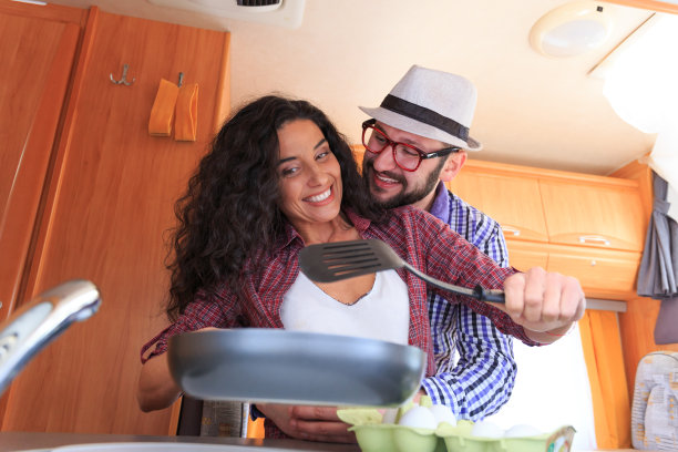 微笑的夫妇有乐趣和烹饪在一个露营图片下载