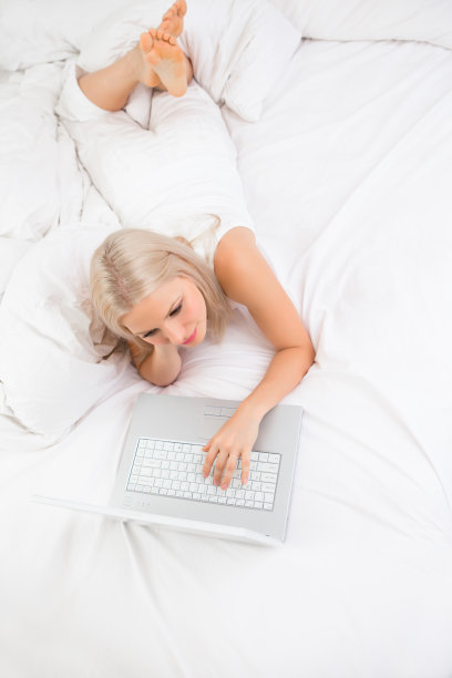 沉思的中年妇女躺在床上上网图片下载