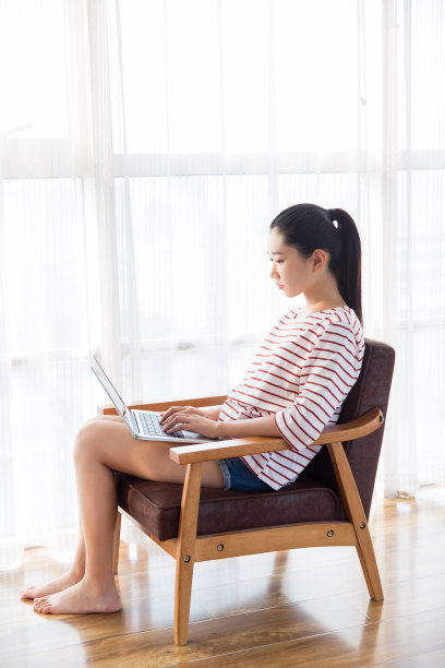 年轻女子工作与笔记本电脑在扶手椅在家里图片下载