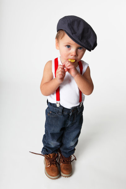 穿着牛仔裤，戴着帽子，拿着棒棒糖的小男孩图片下载