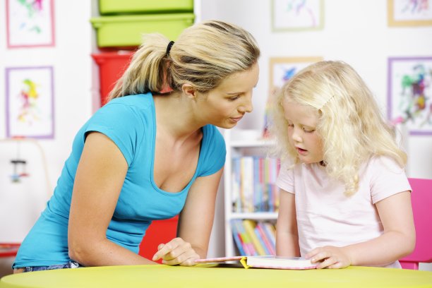 金发小女孩和看护者看书的肖像图片下载