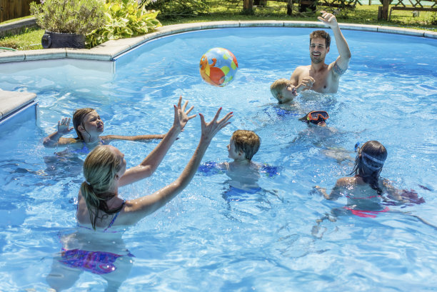 年轻的家庭在游泳池里玩球素材图片