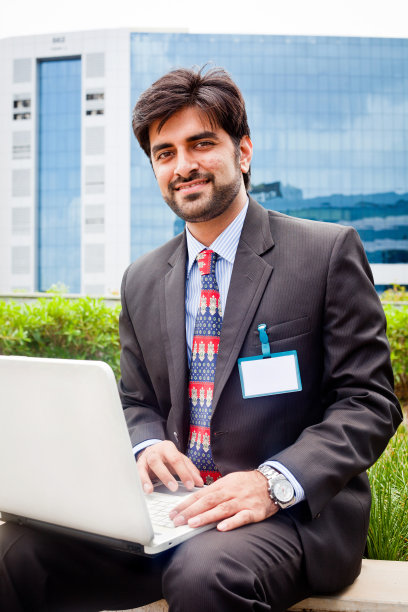 年轻的亚洲印度商人坐在户外使用笔记本电脑图片下载