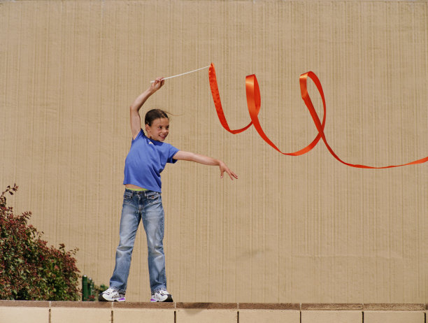 女孩(7-9)站在墙上，假装做艺术体操图片下载