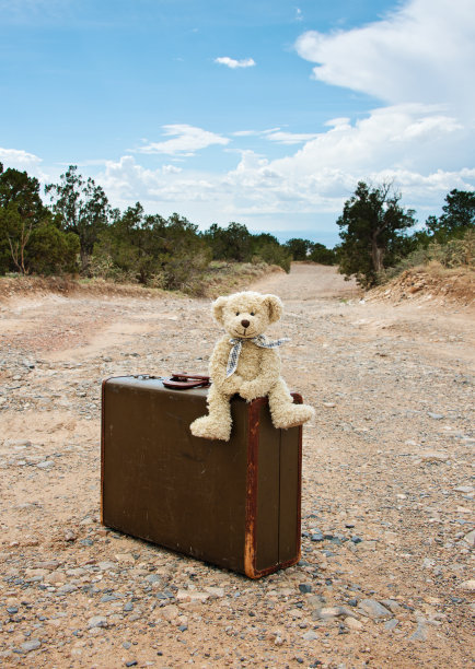 泰迪熊旅行，旧行李箱在土路上图片下载