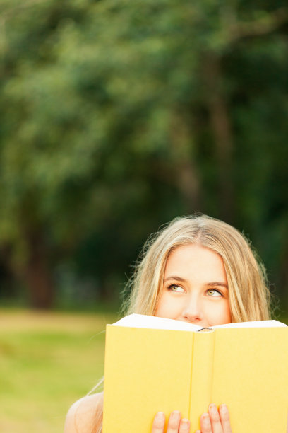 心神不定的年轻女子在花园里看书图片下载