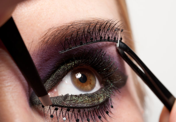 漂亮的年轻女子在戴假睫毛。图片下载