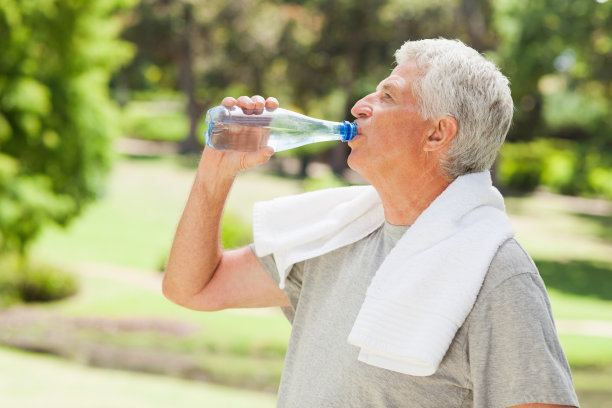 一个男人在公园里喝水的侧面照片图片下载