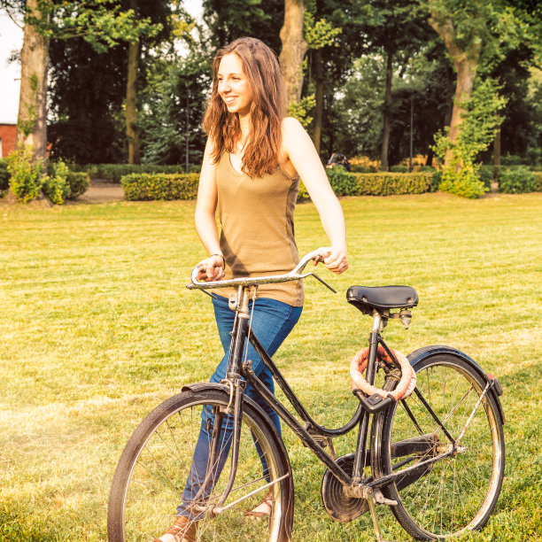 快乐的年轻女子在公园骑自行车图片下载