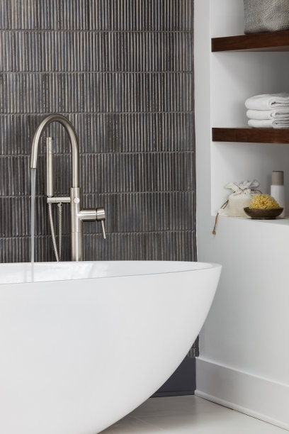 现代的现代浴缸，水从不锈钢水龙头流出。素材图片