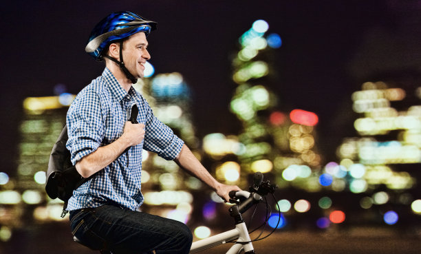 微笑的自行车手在城市的夜晚骑着自行车图片下载