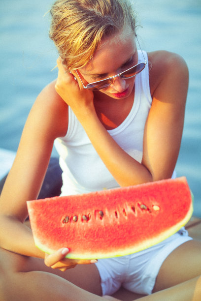 码头上一个兴高采烈的年轻女子，手里拿着一个多汁的西瓜图片下载