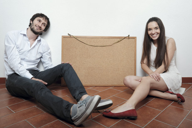 一对夫妇坐在地板上-软木板copyspace图片下载