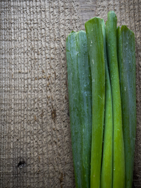 绿色的葱在棕色的木背景上素材图片