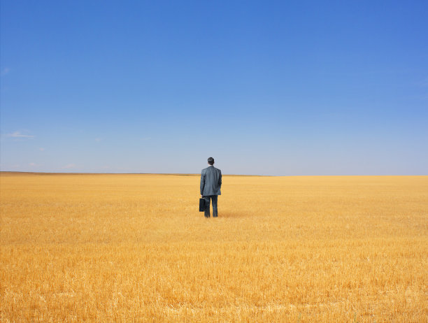 商人站在棕色的草地中间图片下载