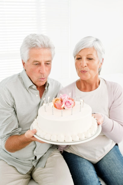 一对老夫妇在吹蛋糕上的蜡烛图片下载