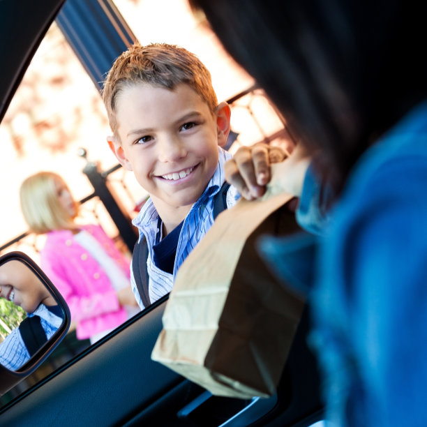 在拼车队伍中，妈妈递给正在上小学的儿子午餐图片下载