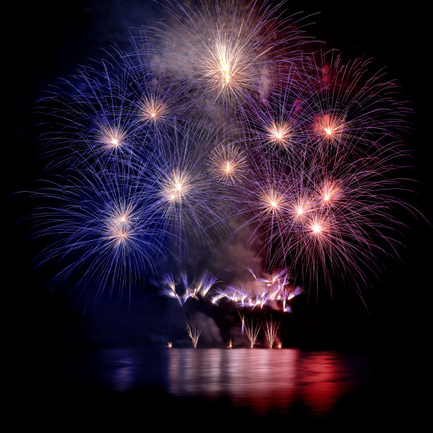 美丽的蓝、白、红相间的大型烟花与水的倒影图片下载
