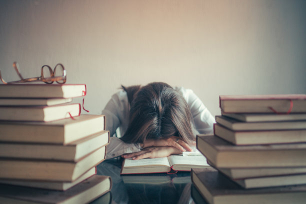 疲惫的女学生在桌子上睡觉图片下载