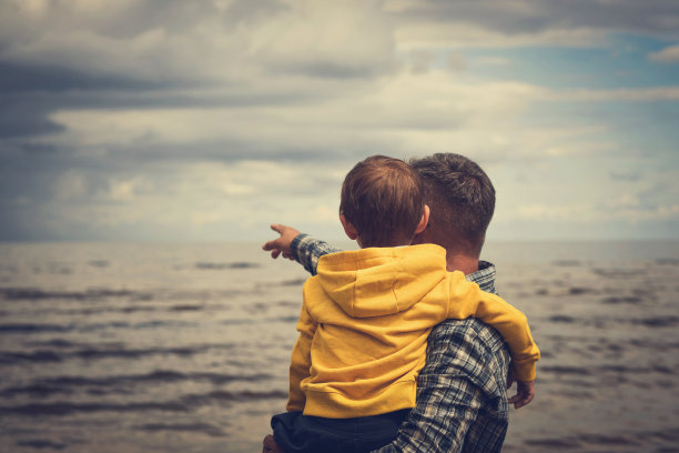 父亲和儿子在享受海滩上的景色图片下载