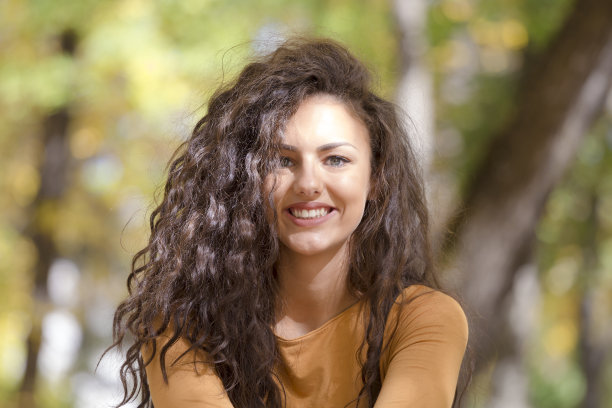 美丽的微笑卷曲的女孩在秋天的森林户外肖像。图片下载