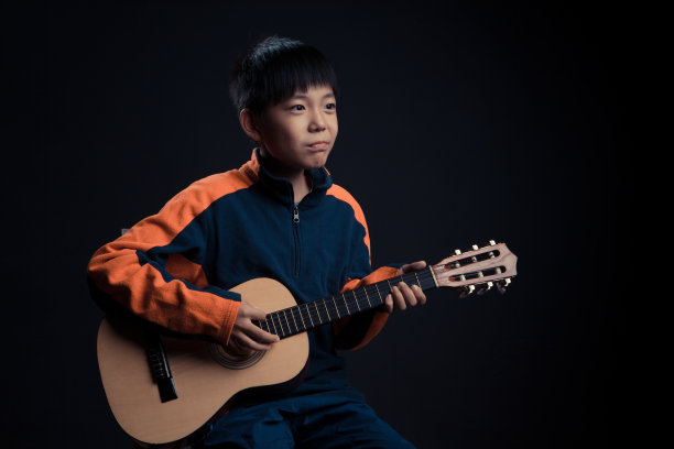 英俊的快乐男孩正在弹原声吉他图片下载