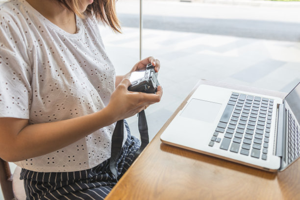女性在笔记本旁边预览图片时使用相机图片下载