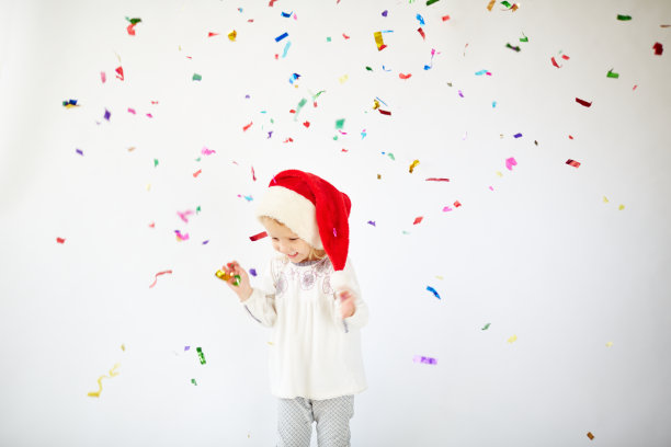 小可爱戴着圣诞帽享受飘落的五彩纸屑图片下载