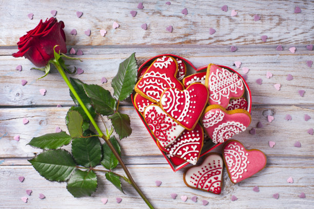 旧木桌上放着心形饼干和玫瑰花素材图片