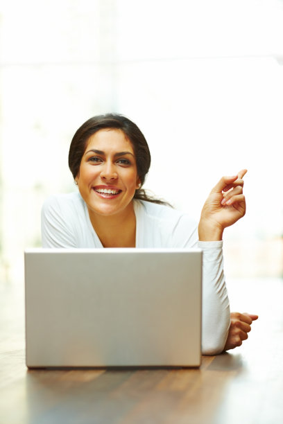 年轻女子在笔记本电脑前微笑并打手势示意图片下载