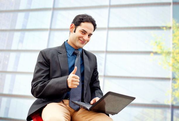 聪明的印度商人使用笔记本电脑显示大拇指向上的手势图片下载