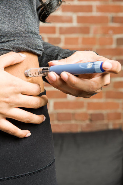 年轻的东亚妇女使用胰岛素笔图片下载
