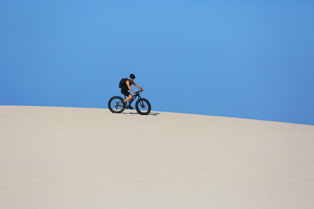 男人骑着山地车在沙丘上骑车图片下载