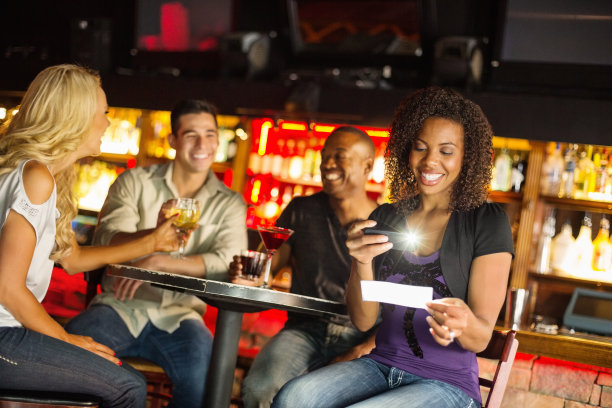 快乐的女人在夜总会通过智能手机存款支票图片下载