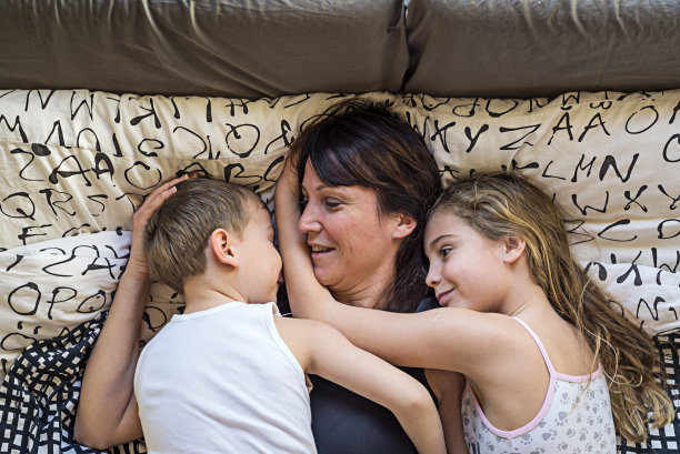 快乐的妈妈和她的孩子们躺在床上图片下载