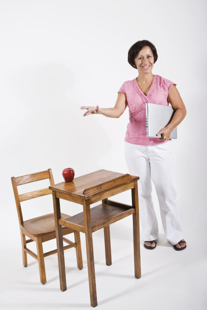 小学老师站在孩子的课桌旁图片下载