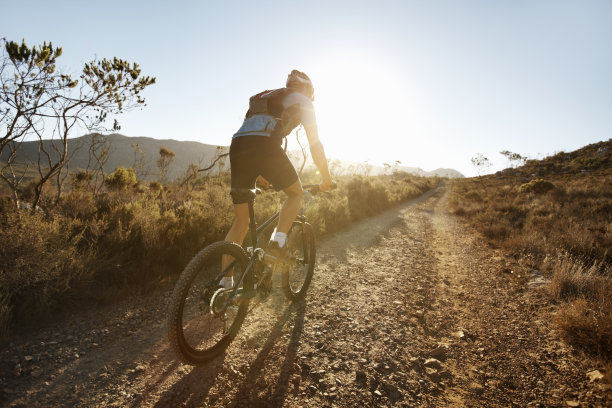 日落时分，骑自行车的人在砂砾小道上骑行图片下载