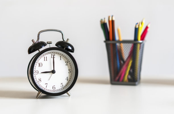 书桌上有闹钟和彩色铅笔图片下载