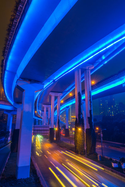 中国上海，在霓虹灯照亮的未来城市景观高速公路上，车辆疾驰而过图片下载