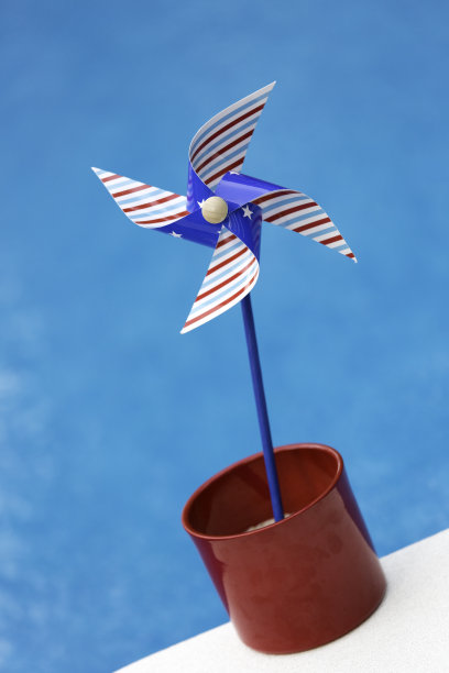 红色，白色和蓝色的风车在水池边图片下载