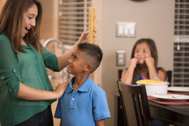 母亲用码尺量儿子的身高。首页图片下载