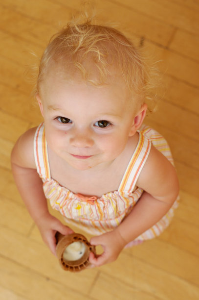 蹒跚学步的孩子吃着蛋筒冰淇淋图片下载