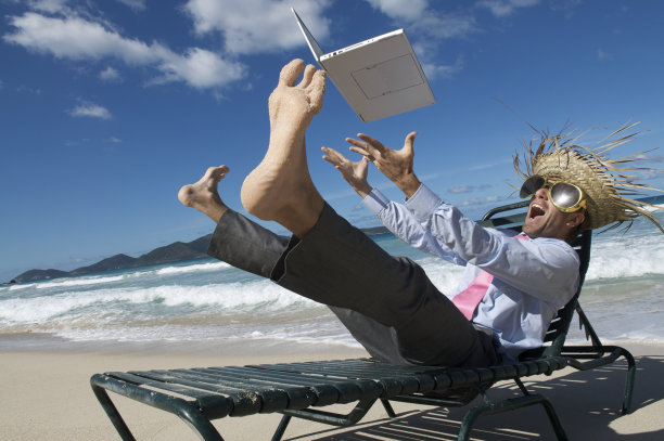 疯狂的旅游商人把他的笔记本电脑扔到热带海滩上图片下载