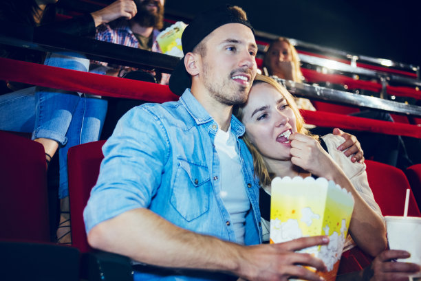 一对夫妇在电影院边看电影边吃爆米花图片下载