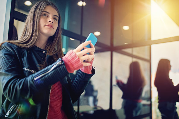 一个十几岁的女孩在镜子的窗户前发短信，做出美丽的映像图片下载