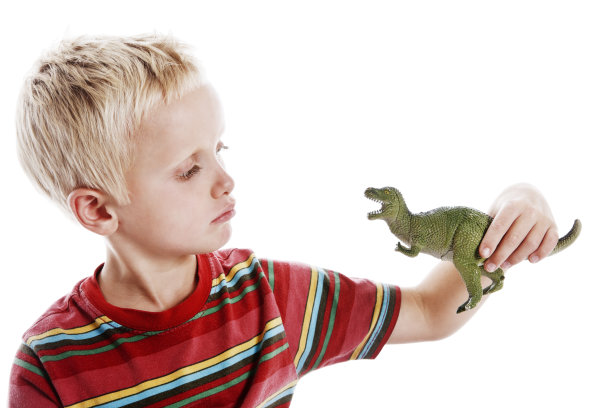 可爱的6岁金发男孩检查玩具恐龙图片下载