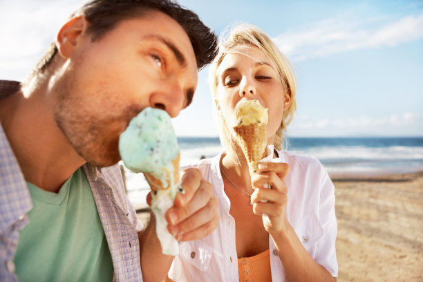 年轻夫妇在海滩上吃冰淇淋图片下载