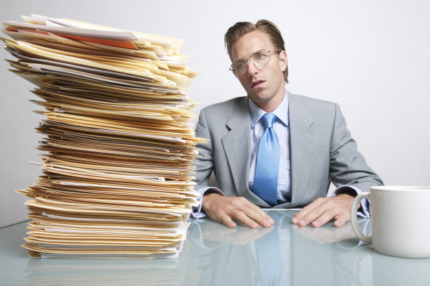 无聊的商人办公室职员坐在办公桌前看文书工作图片下载